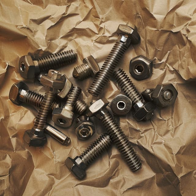 Tornillos de metal siendo envueltos en un papel VCI kraft