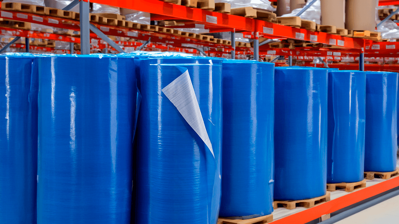 Rollos de tela vci tejida siendo almacenados en una industria